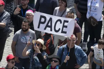 Peregrinos na praça de São Pedro com faixa que diz "Pace"