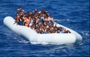 Migrantes a bordo de barco inflável no mar Mediterrâneo aproximam-se de um navio de guerra dos EUA.