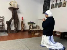 Freira se ajoelha diante de sacrário depois de convidar um grupo de mulheres que doam presentes de Natal a rezar na casa das missionárias da Caridade em Roma.
