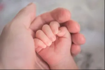 Mão segurando mão de bebê