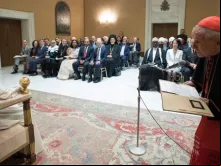 Cardeal Tauran fala diante do Papa Francisco durante encontro inter-religioso.