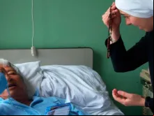 Religiosa rezando com um doente