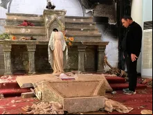 Sacerdote olhando para uma imagem da Virgem Maria decapitada, entre os escombros de uma igreja destruída pelo Estado Islâmico no Iraque.