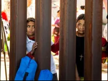 Crianças observam ato inter-religioso do lado mexicano do muro na fronteira.
