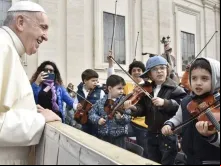 Papa observa algumas crianças tocando instrumentos musicais.