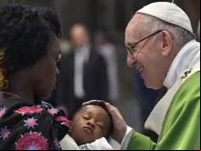 Papa saúda uma mulher migrante e seu filho.