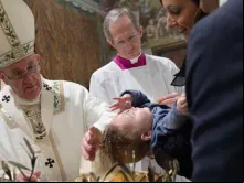 Papa Francisco batiza uma das 28 crianças às quais istrou o sacramento neste domingo na Capela Sistina.