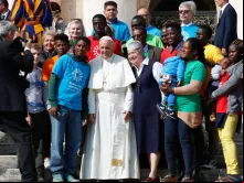 Papa tira uma foto com alguns imigrantes na Praça de São Pedro.