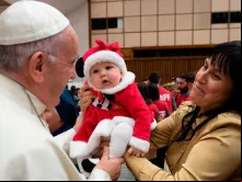 Papa Francisco abençoa uma criança na Sala Paulo VI.