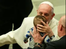 O Papa Francisco beija um menino no Sala Paulo VI.