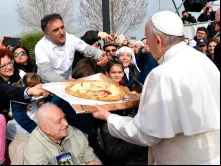 Um homem presenteia o Papa com uma pizza, na qual está desenhado o rosto do Pontífice e de Padre Pio.