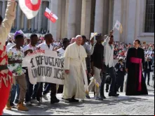 Papa sobe ao palco junto ao grupo de refugiados.