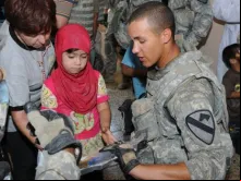 Soldado americano entrega material escolar para crianças no Iraque.